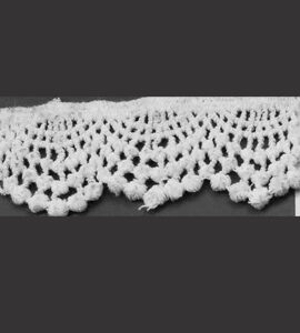 A detailed close-up of a white floral chemical lace sample on a dark background, showing the intricate embroidery and texture.
